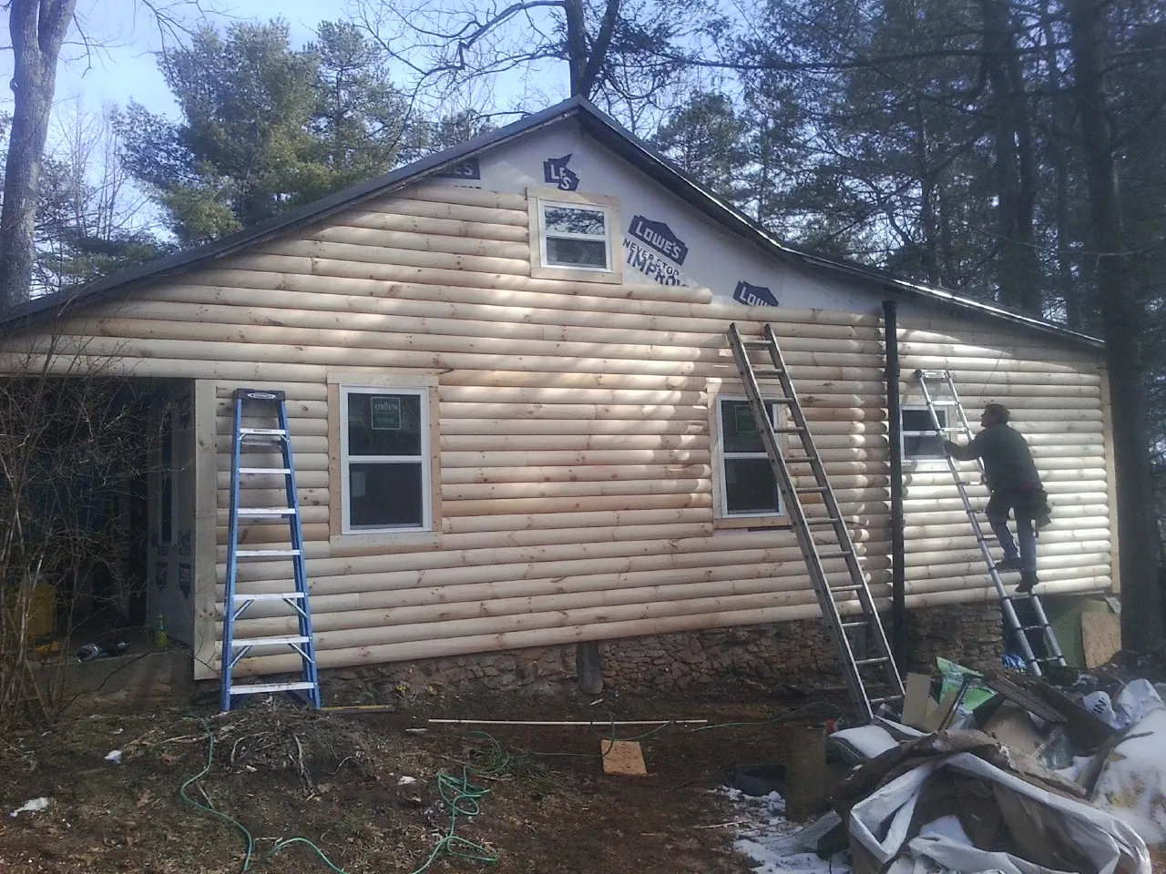 Ladders set against fresh log siding during an exterior remodel in Gunnison